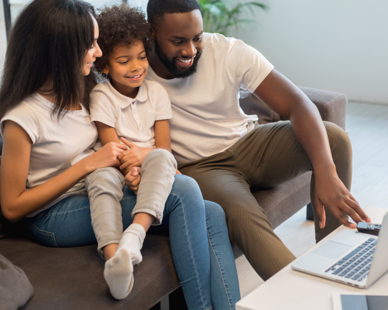 Family watching TV or using a laptop together on a sofa.