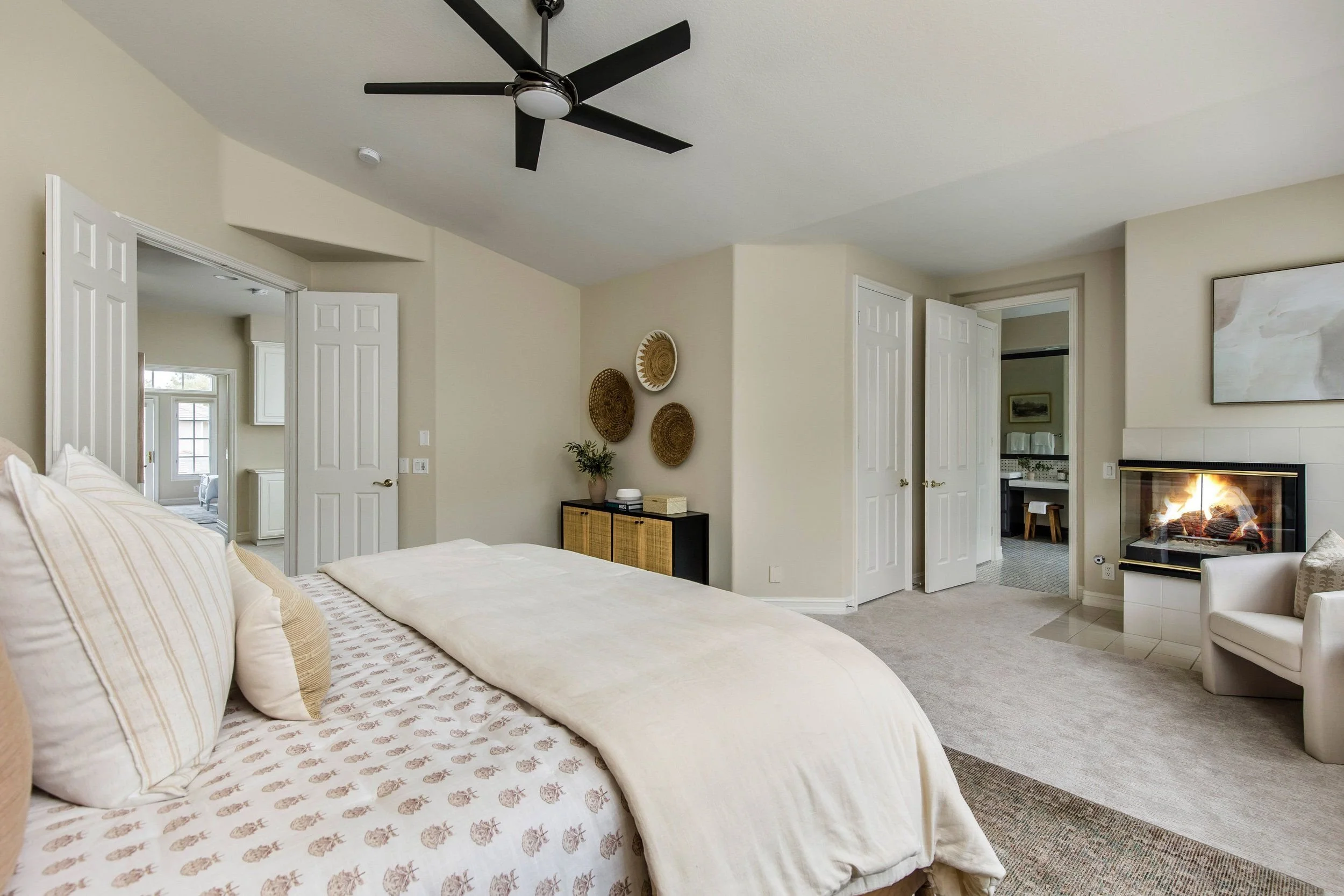 Living room with a bed, open doors, a fireplace, wall decor, and ceiling fan.