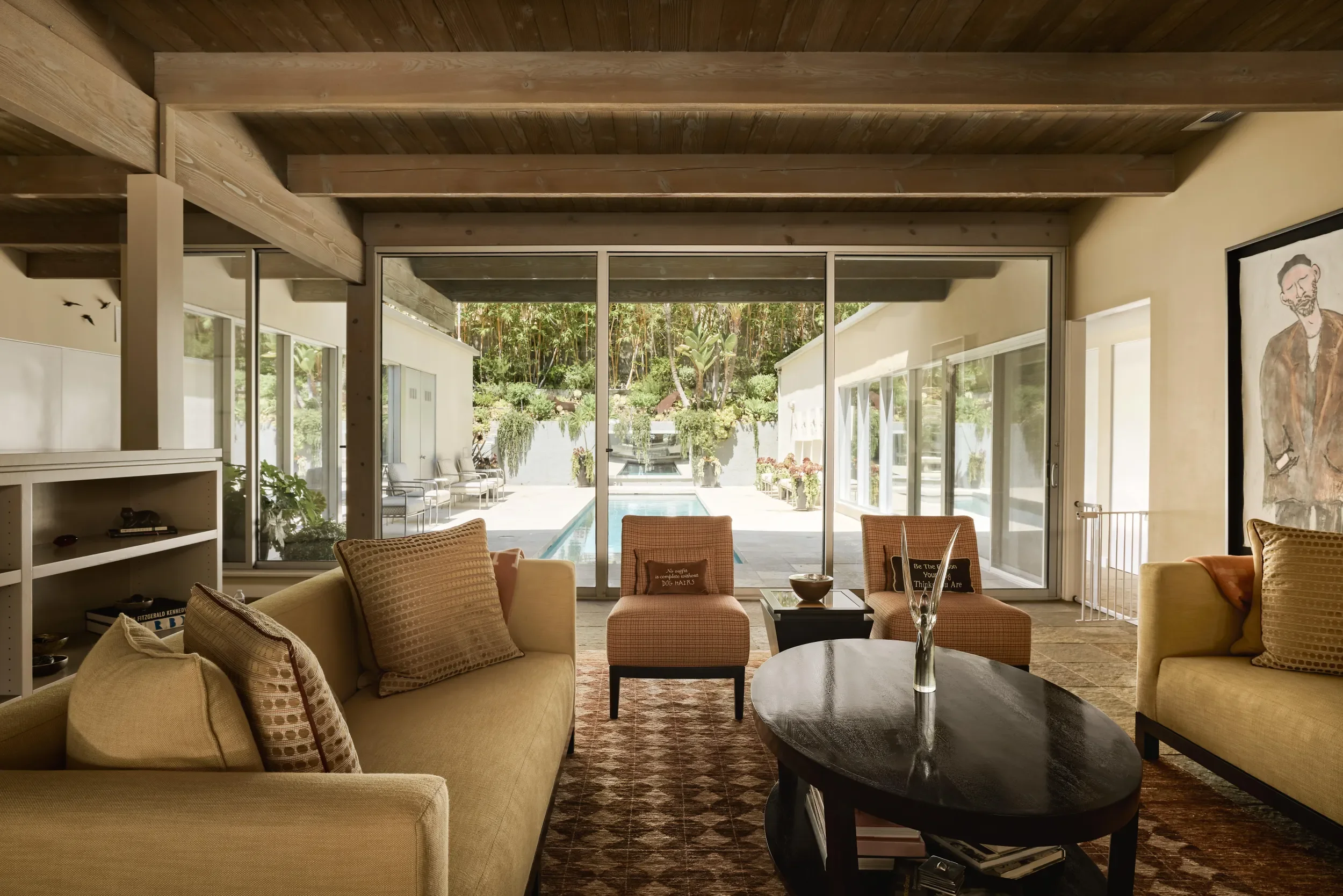 Living room with beige sofas, throw pillows, and a black coffee table, large glass sliding doors opening to outdoor patio and pool