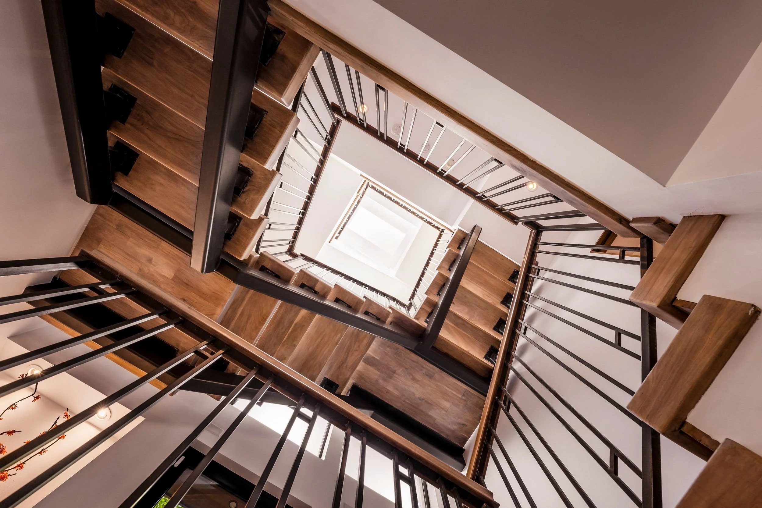 A view looking down a multi-level staircase with wooden steps and black metal railings, creating a spiraling effect.