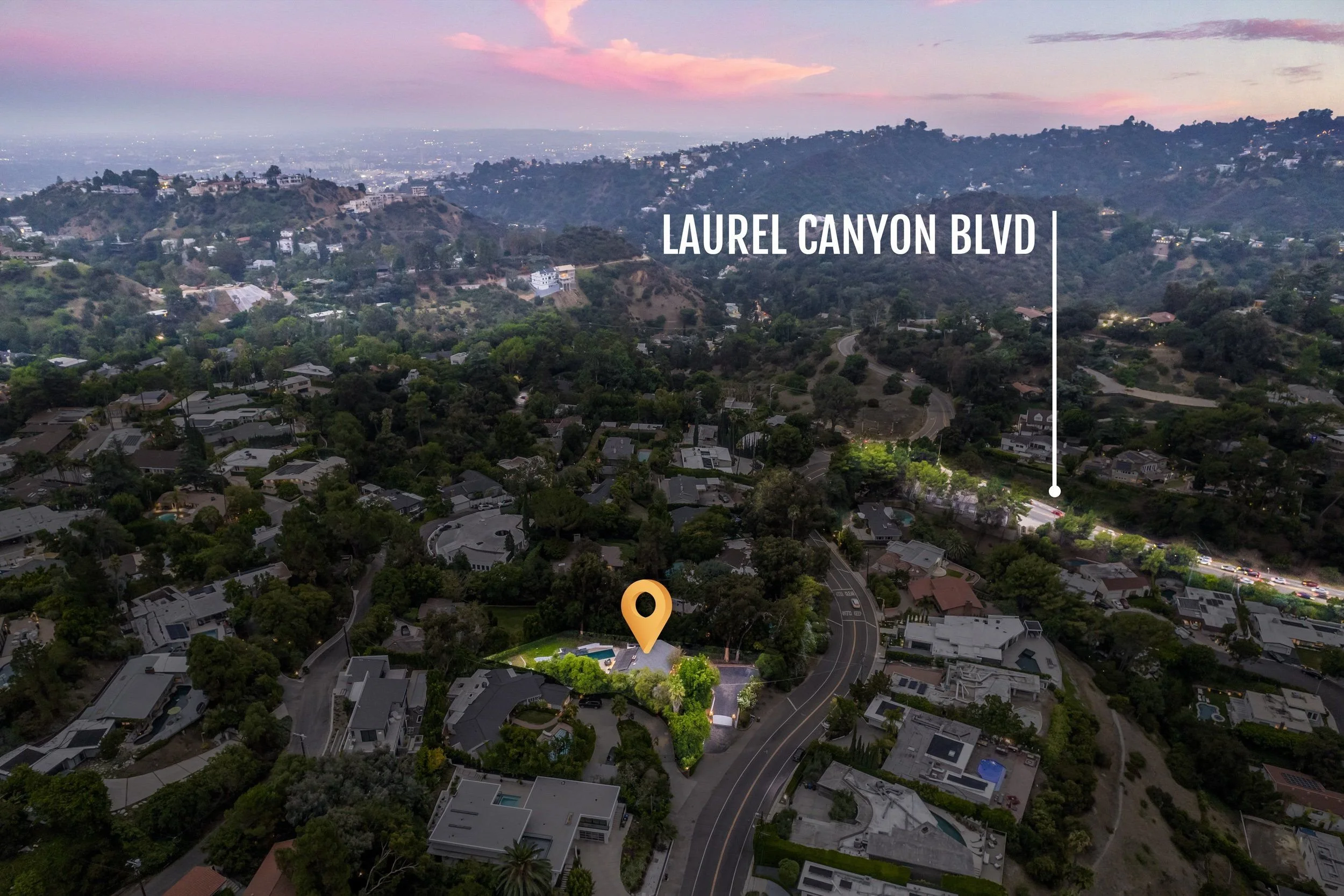 Aerial view of residential neighborhood in Laurel Canyon, Los Angeles, with houses, trees, and winding streets during sunset with pink and purple clouds.