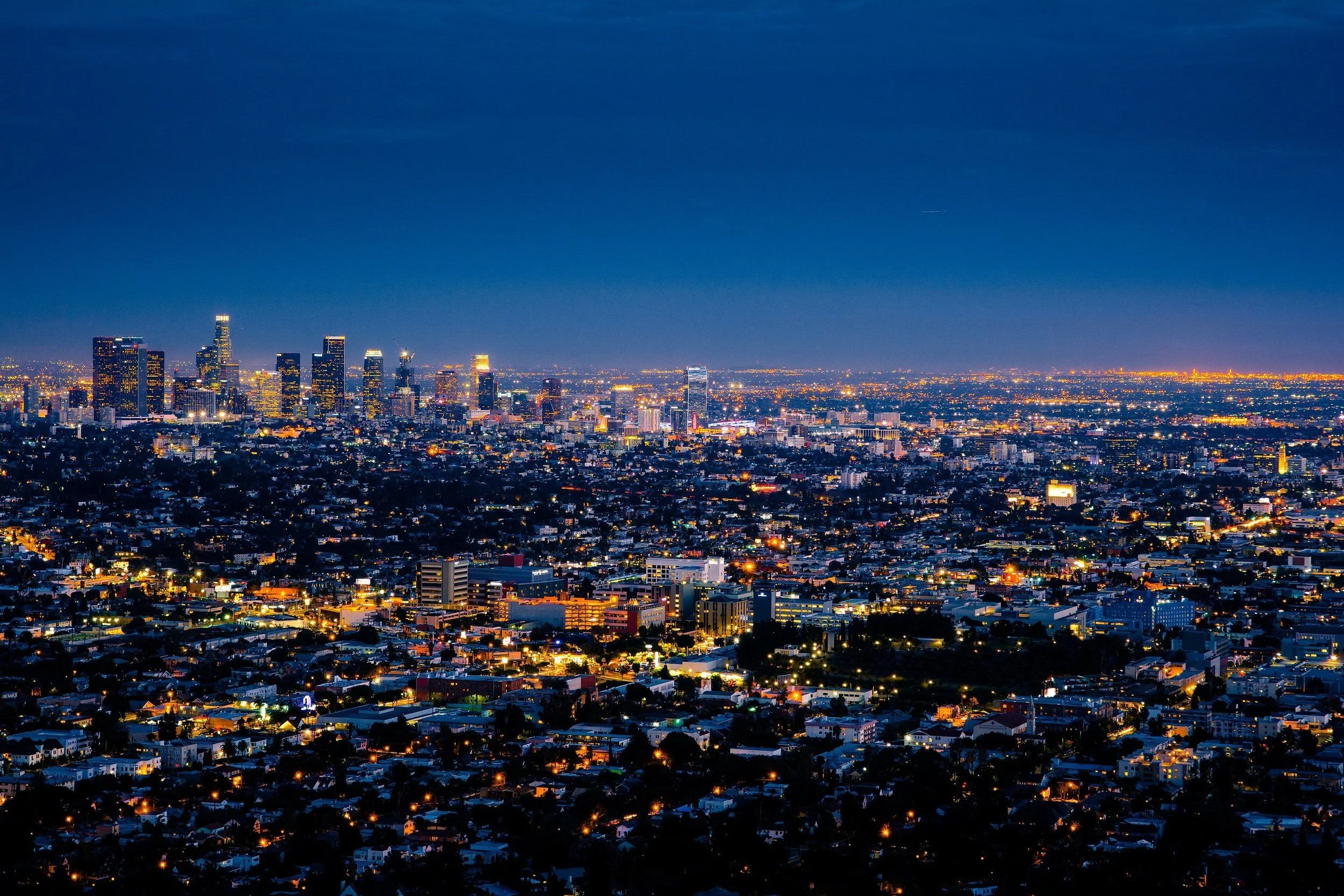 Nighttime cityscape of Los Angeles with illuminated buildings and a clear sky.