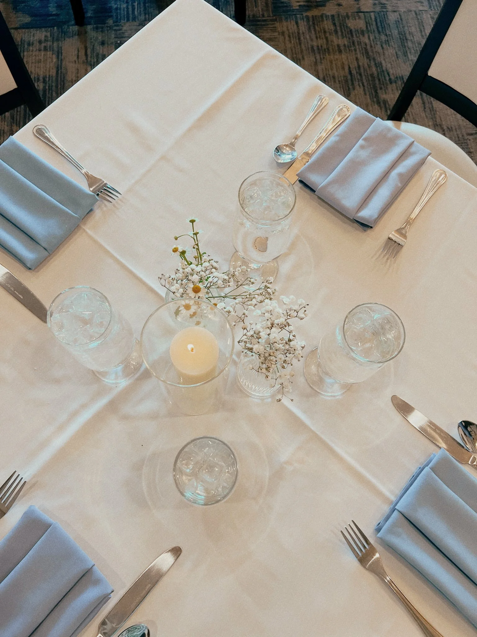 Dinner party tablescape with candles and fresh flowers on a small dining table