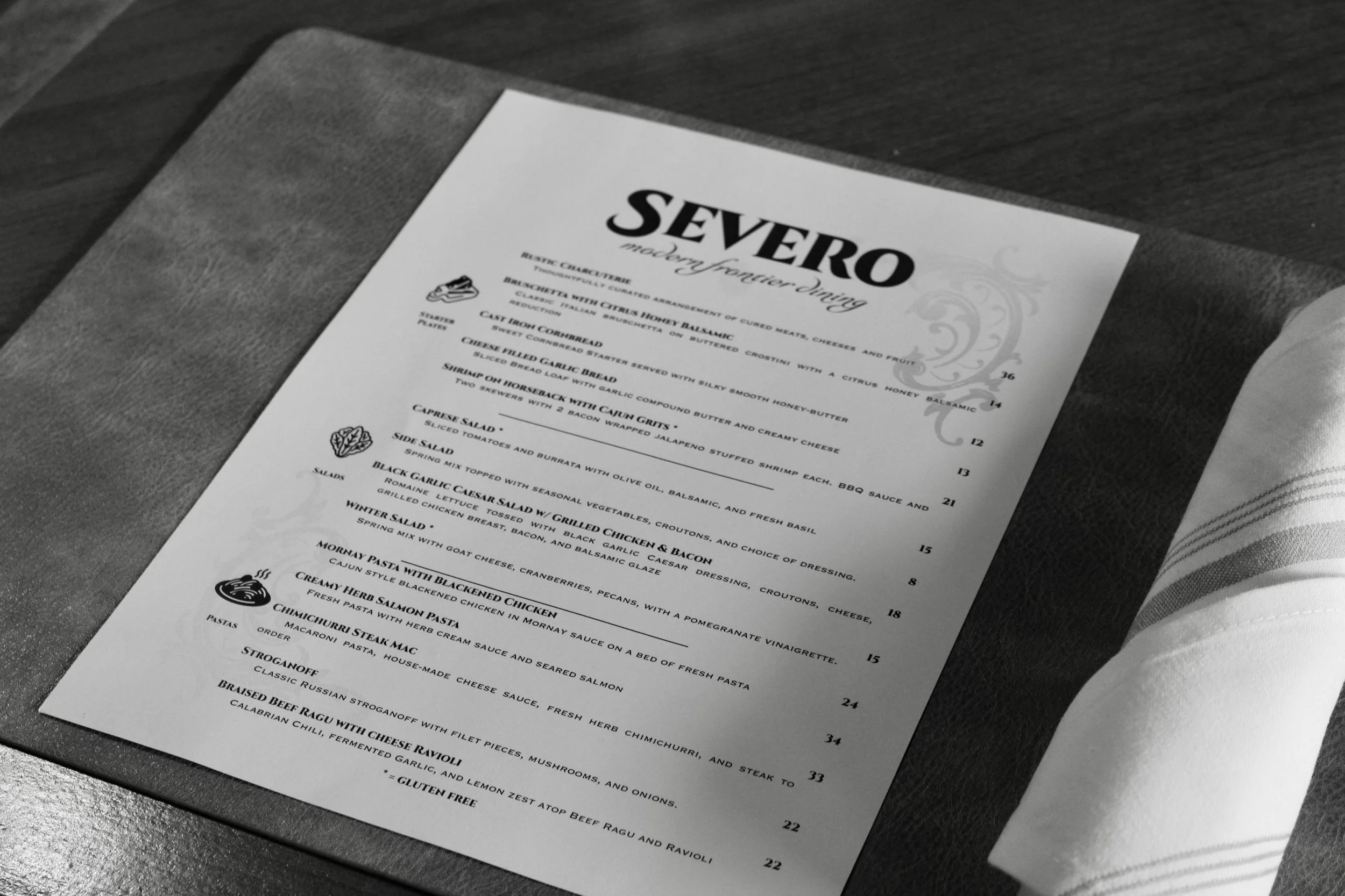 A menu titled 'Severo, Modern Fusion Dining', placed on a dark textured table with a folded cloth napkin beside it.