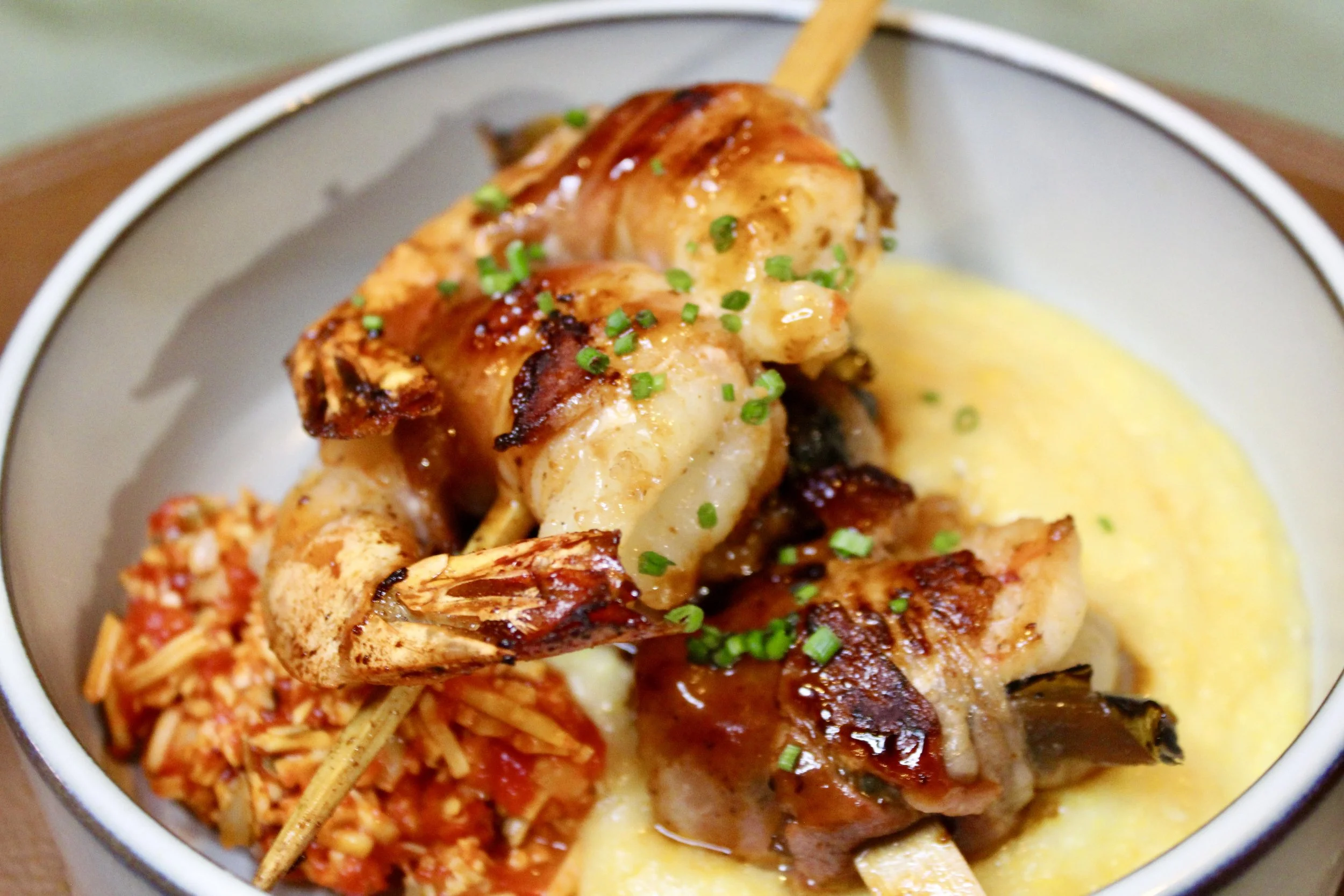 Shrimp and vegetable skewer with mashed potatoes and rice, garnished with chopped green onions