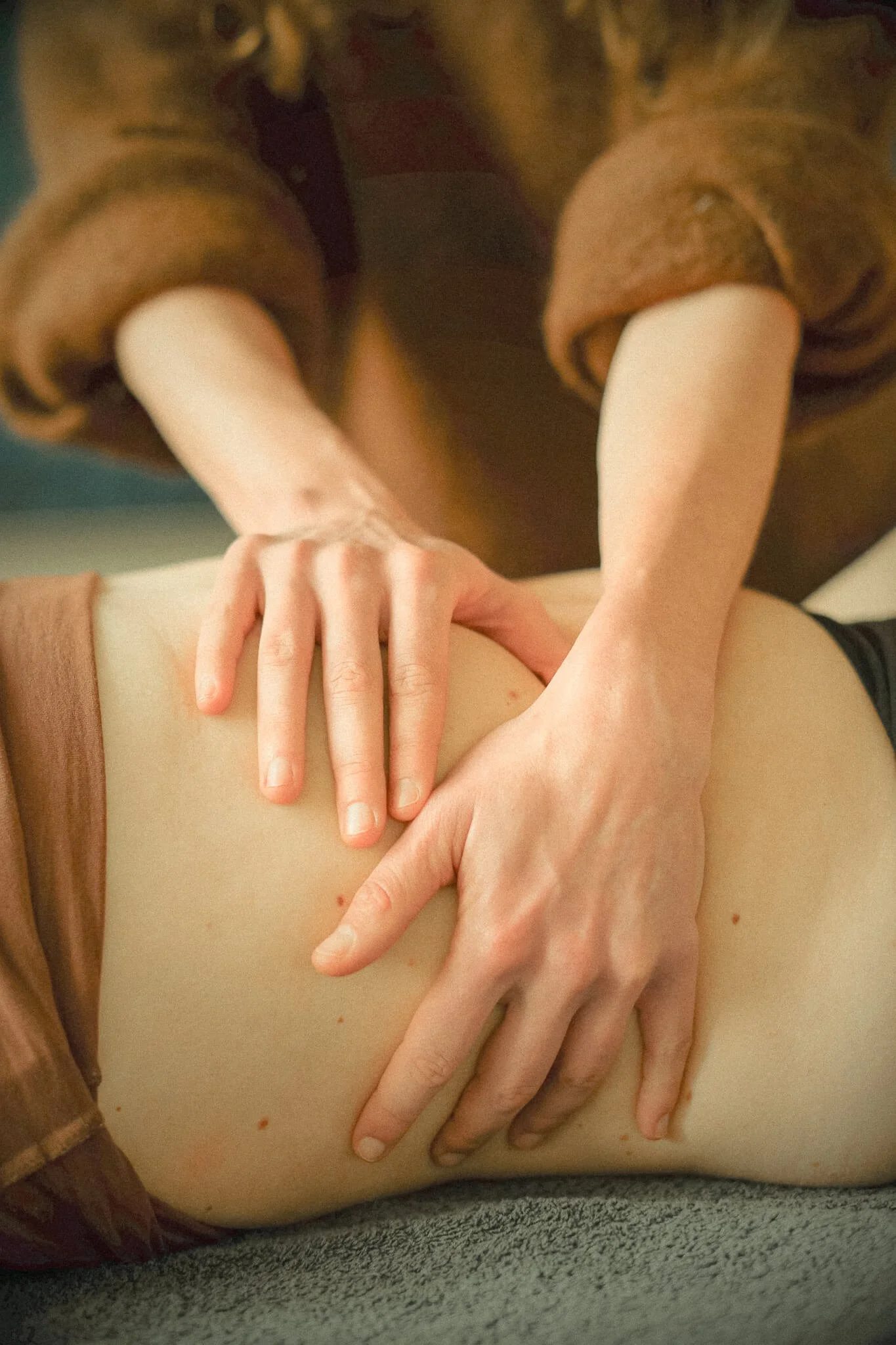 Close-up van meerdere handen die elkaar vasthouden op een buik, mogelijk tijdens een aanraking of massage.
