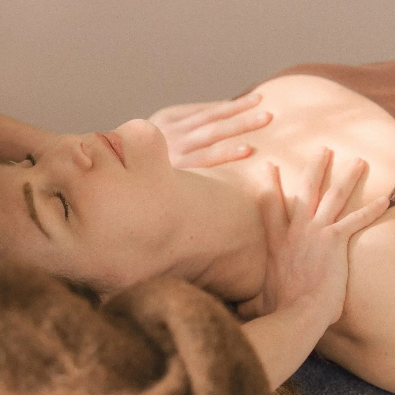 Close-up van een persoon die ontspant met gesloten ogen en haar handen op haar huid, mogelijk tijdens een rustgevende massage of ontspanning.