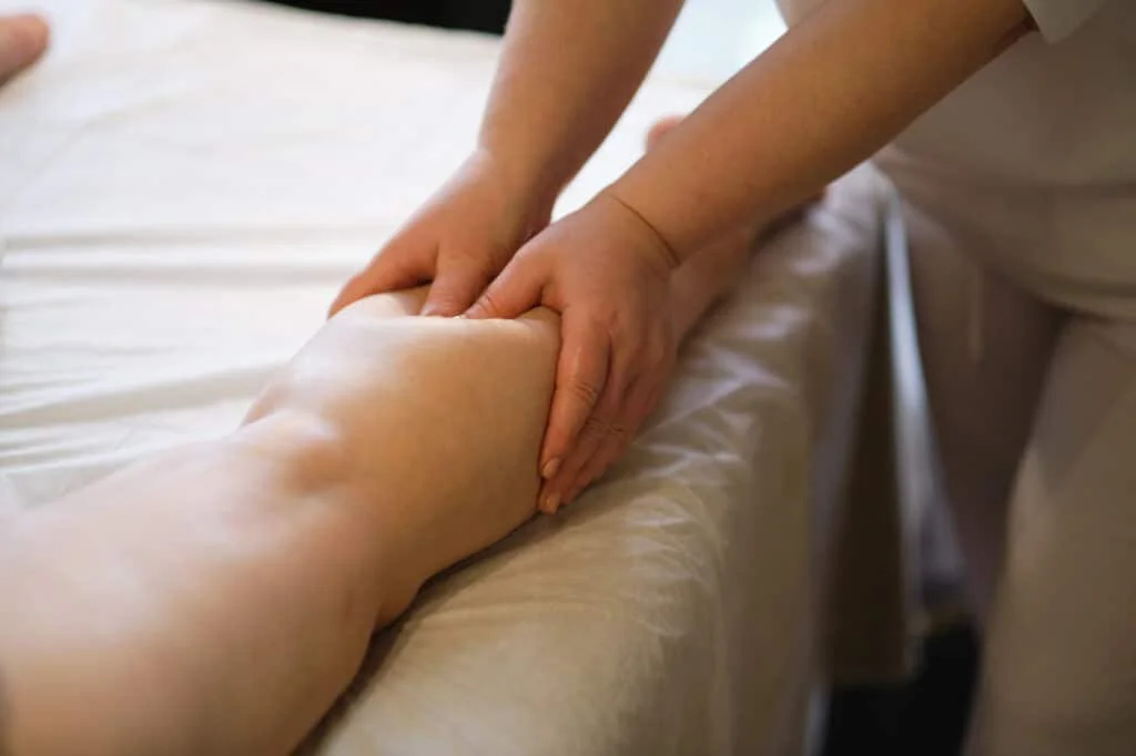 Hands massaging a person's calf muscle during a massage at a spa or wellness center.