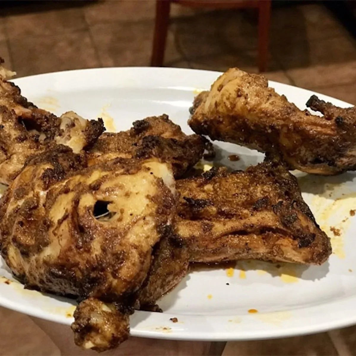 Close-up of grilled chicken drumsticks on a white plate