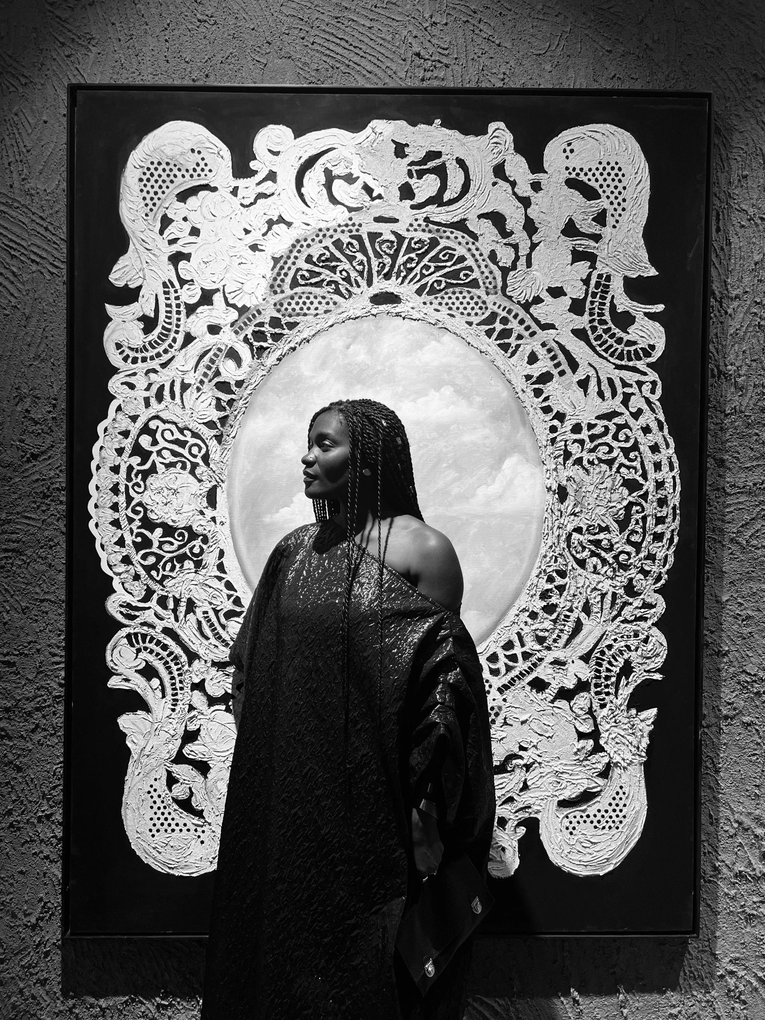 Une femme en robe noire à gauche, devant une œuvre d'art sculpturale dans un musée.