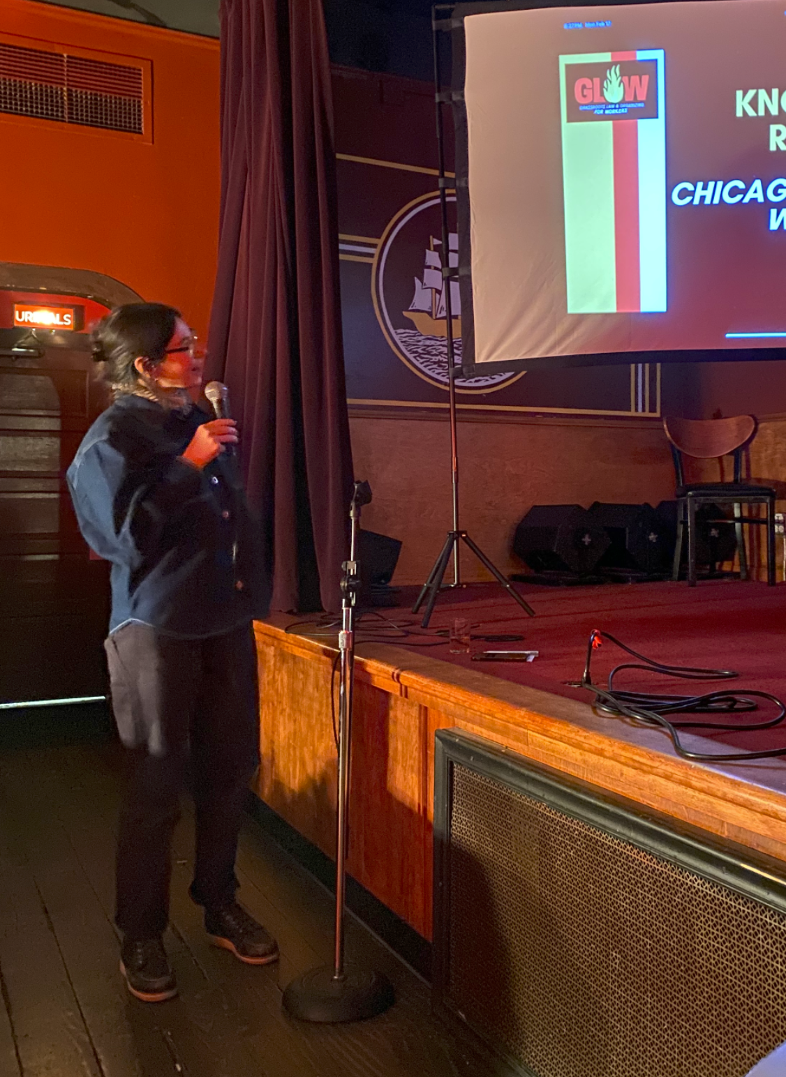 a community member shares "know your rights" slide presentation in a local bar