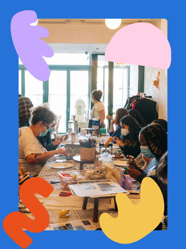 A table of folks wearing masks concentrate on crafts at a CHAAD event