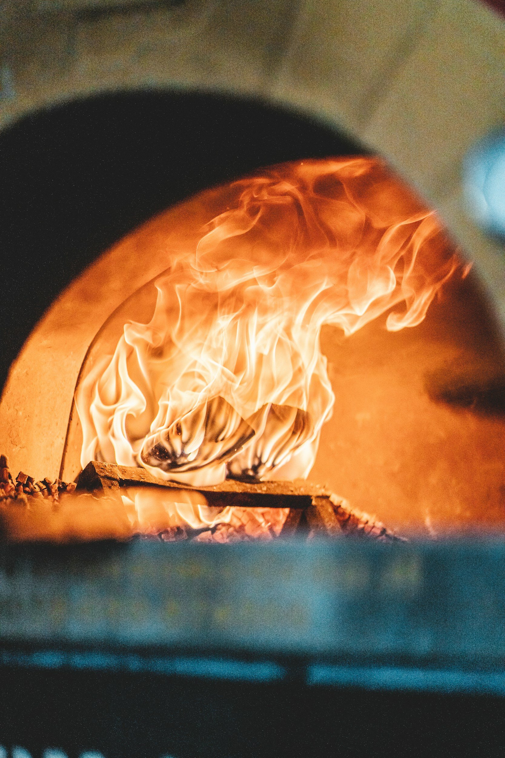 Close-up of a wood-fired oven with visible flames inside.