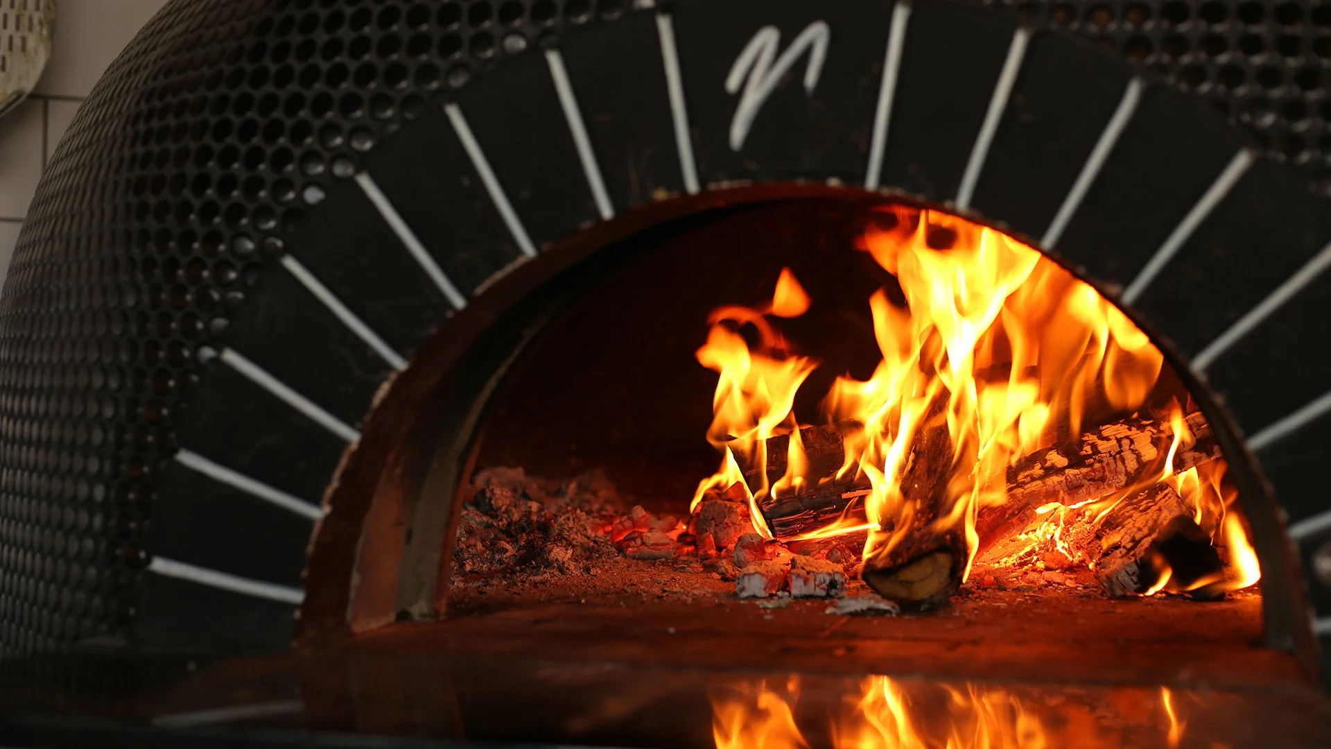 Fire burning inside a black metal firepit with a perforated curved exterior.