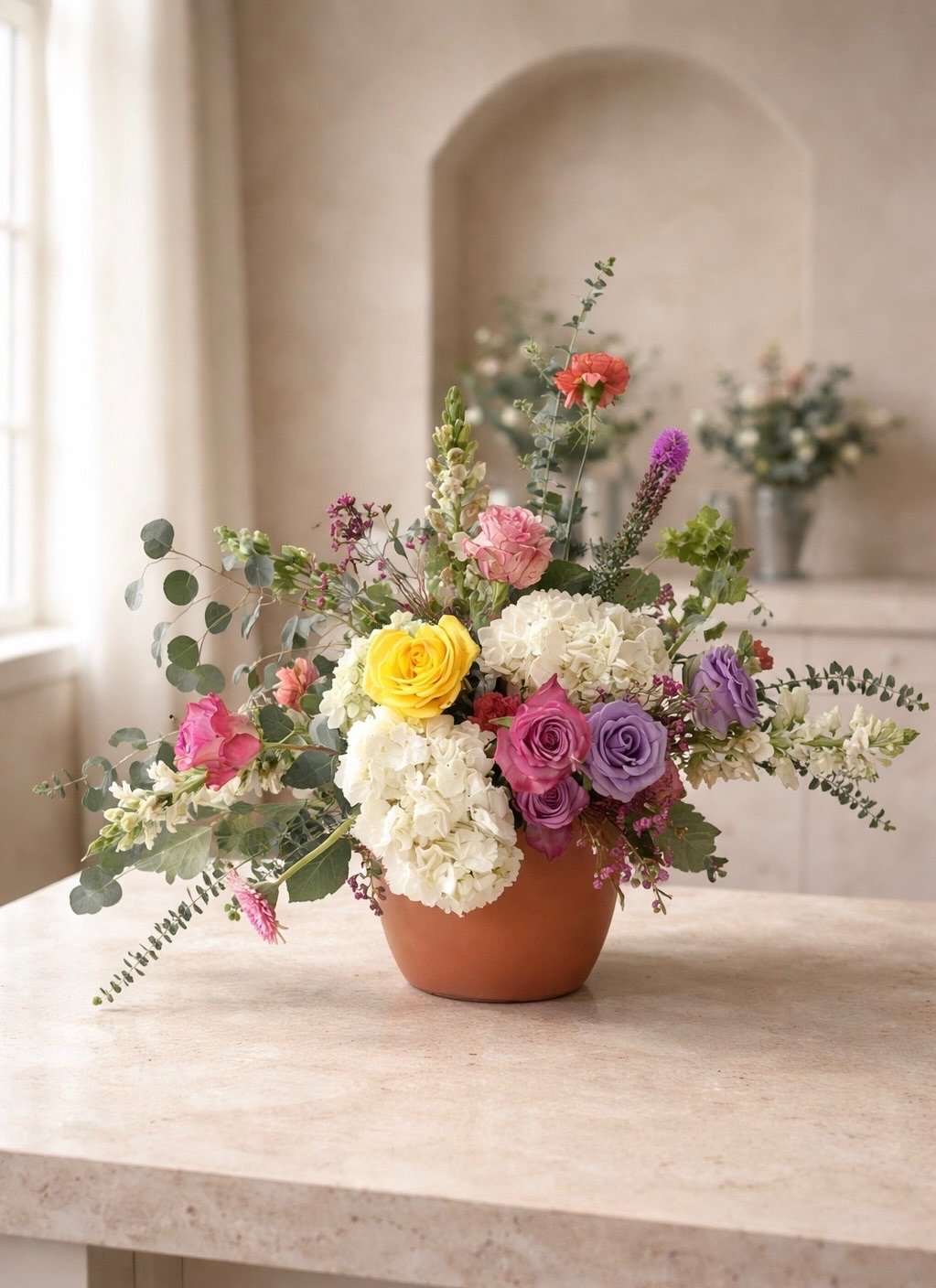 Garden-Inspired custom flower arramgement with soft multicolored blooms and greenery by wedding florist Izalena Floral House.