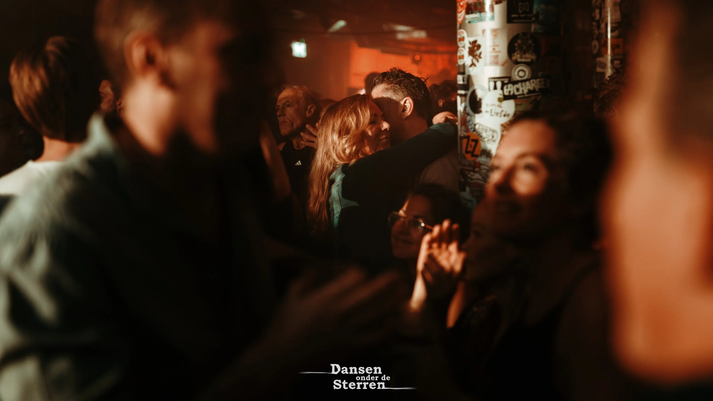 People dancing and socializing in a dimly lit, vibrant nightclub with graffiti-covered walls.