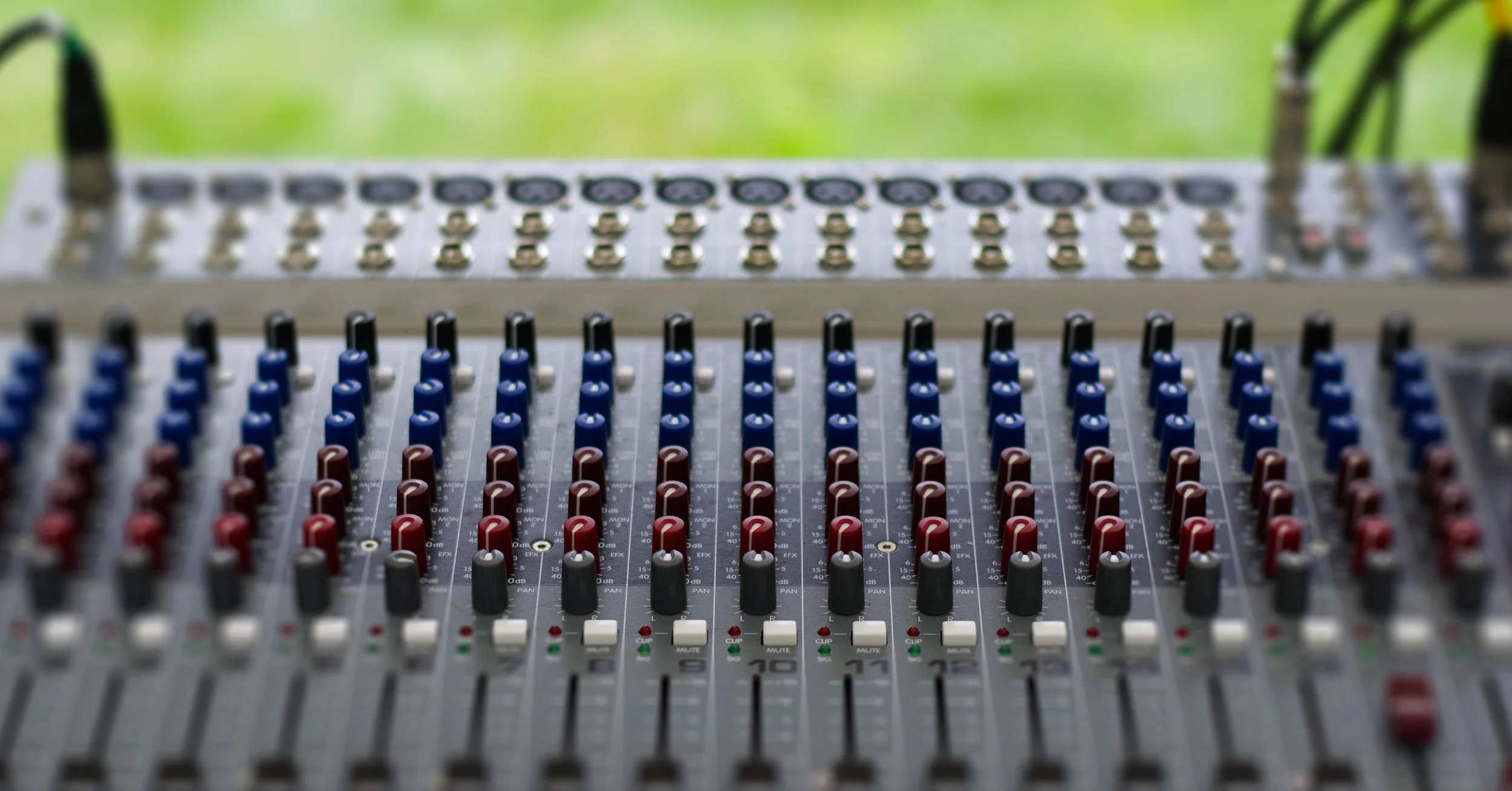 An audio mixing console with numerous knobs, sliders, and buttons for adjusting sound levels.