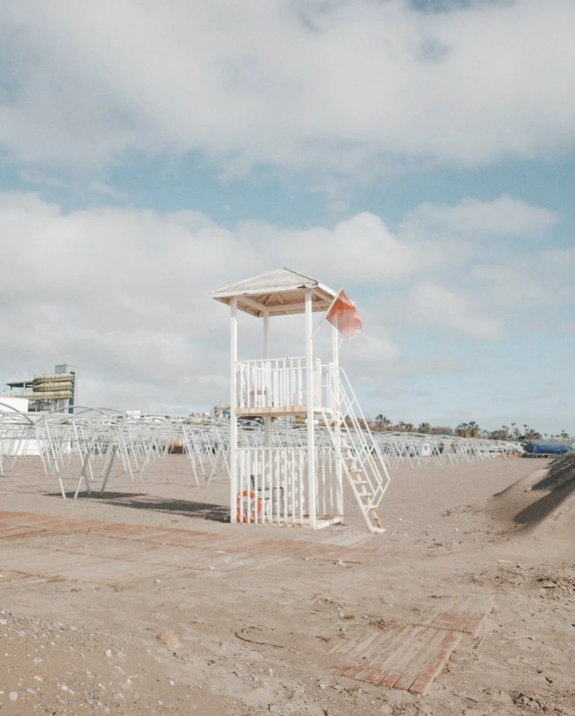 Empty lifeguard tower on the beach under a partly cloudy sky.