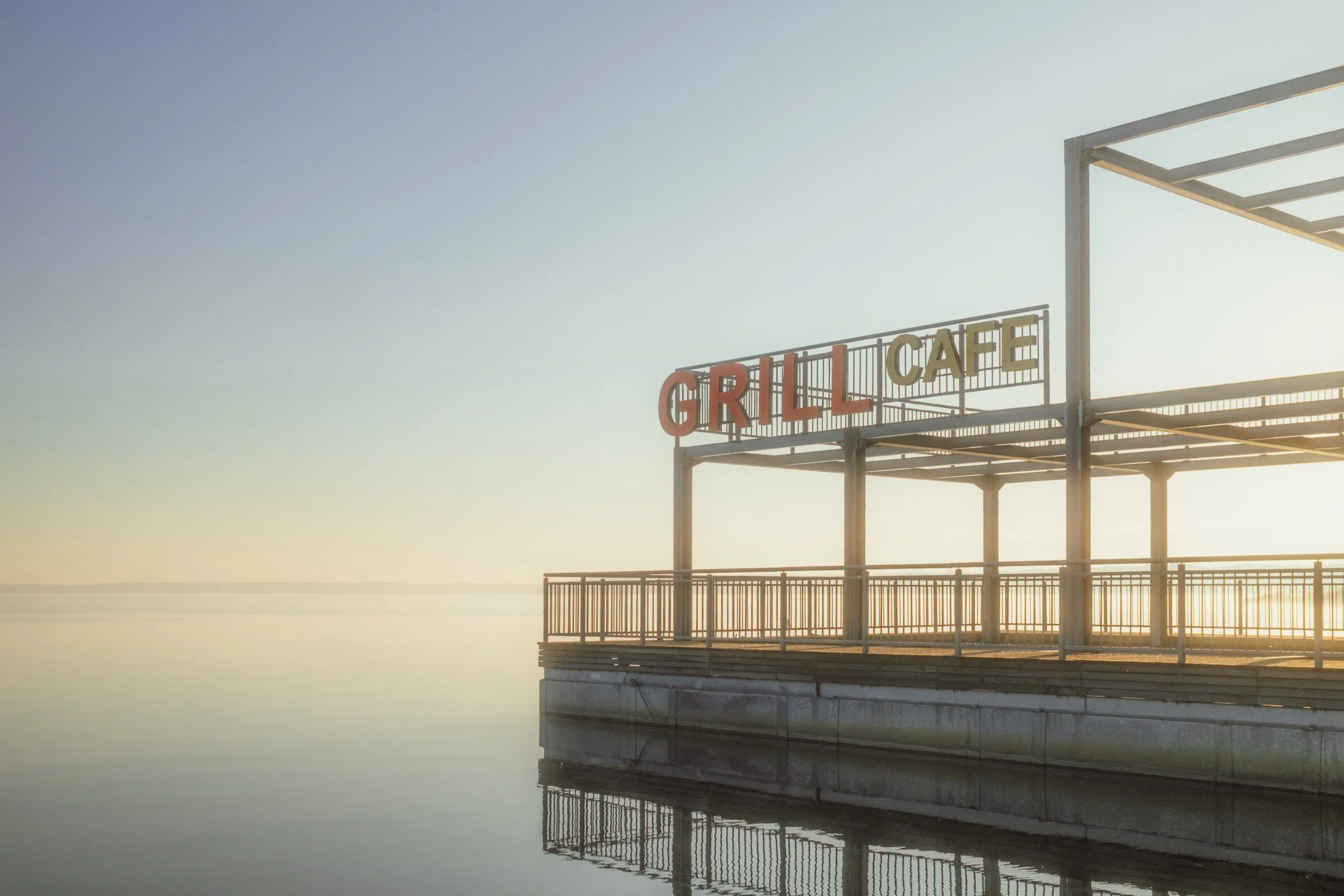 Empty outdoor deck with a large sign that reads 'GRILL CAFE' at sunrise or sunset.