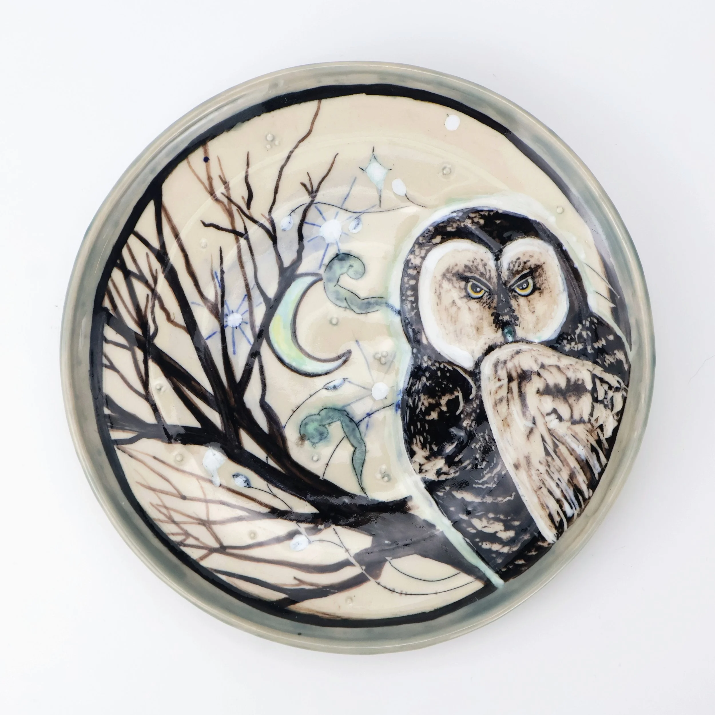 Dinner Plate with Mishima, sgraffito and glaze illustration of a melanistic barn owl, a leafless tree, a crescent moon, and stars against a light background.