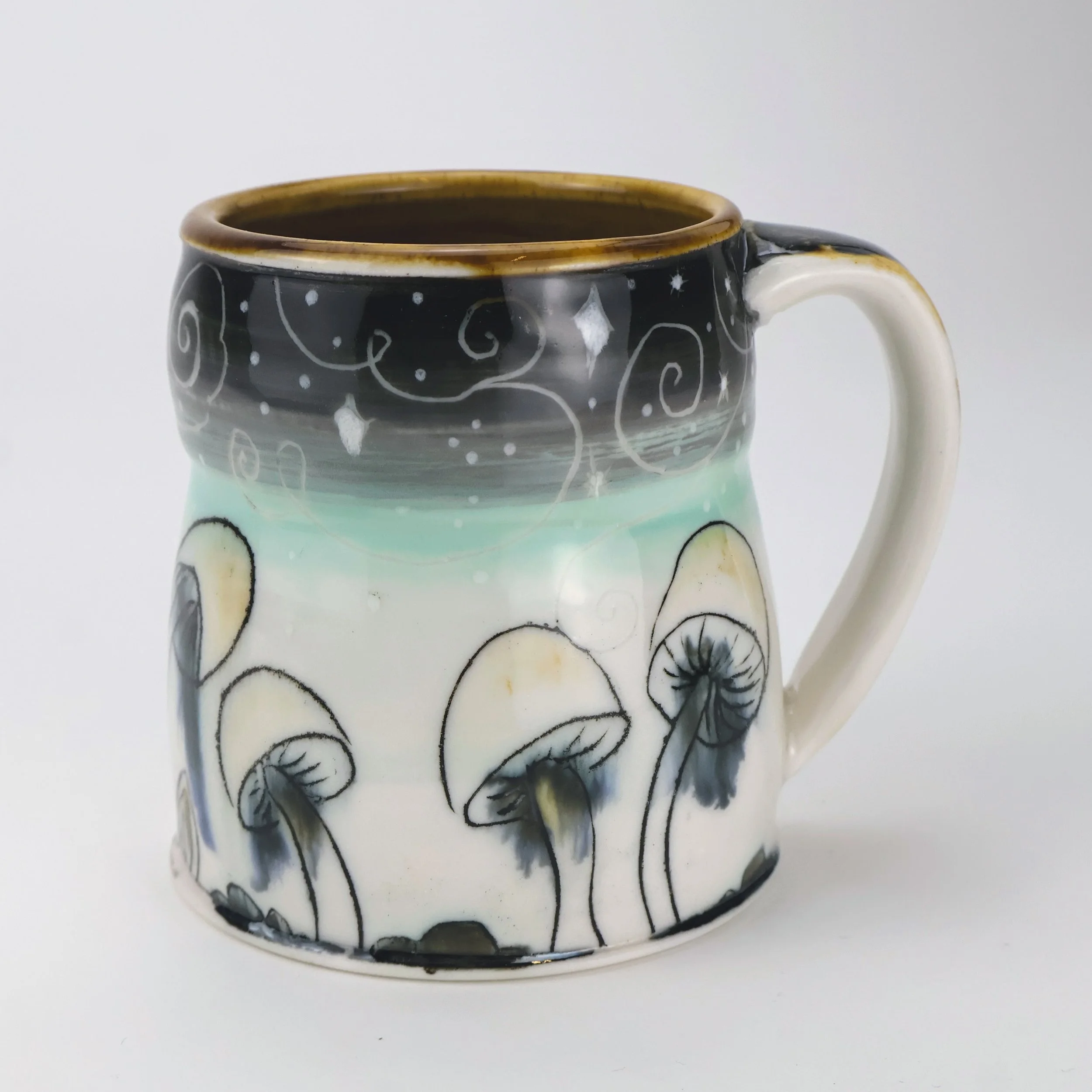 Ceramic mug painted with mushroom illustrations and decorative swirls, black, white, and light blue colors.