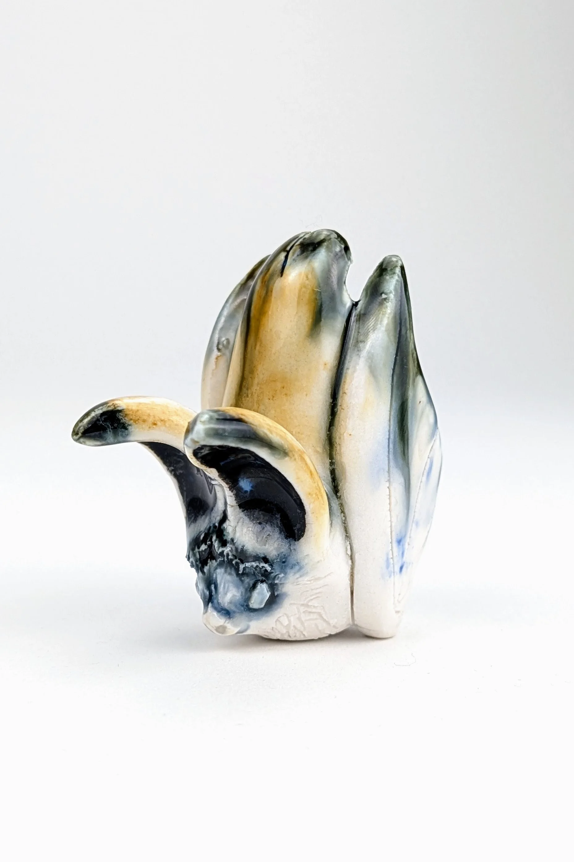 Ceramic porcelain hollow sculpture of a bat with a fluxing clear glaze in earthy and blue tones.