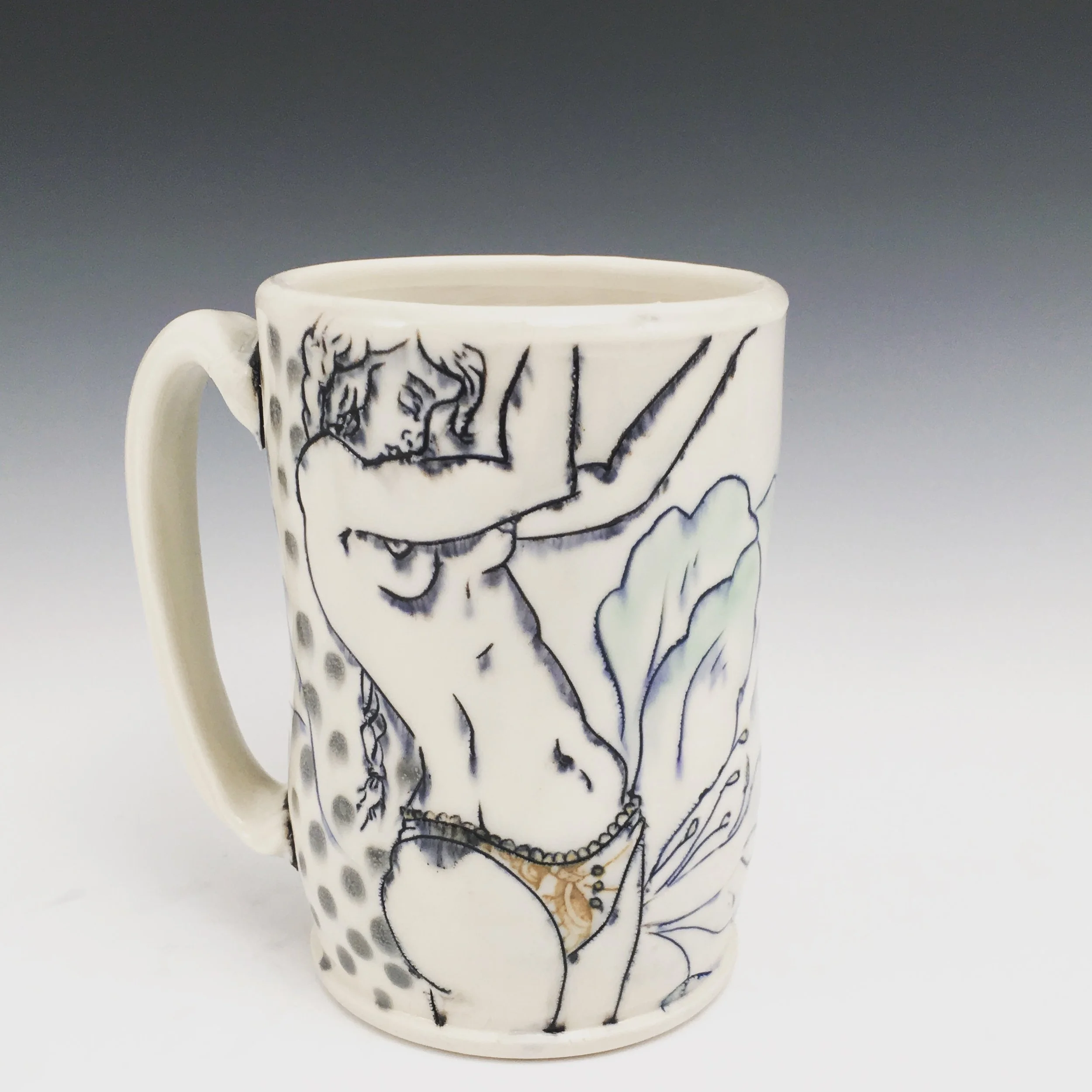 A ceramic mug decorated with line art of a woman with long hair, wearing lingerie, in a pose with one arm raised and her head tilted to the side.