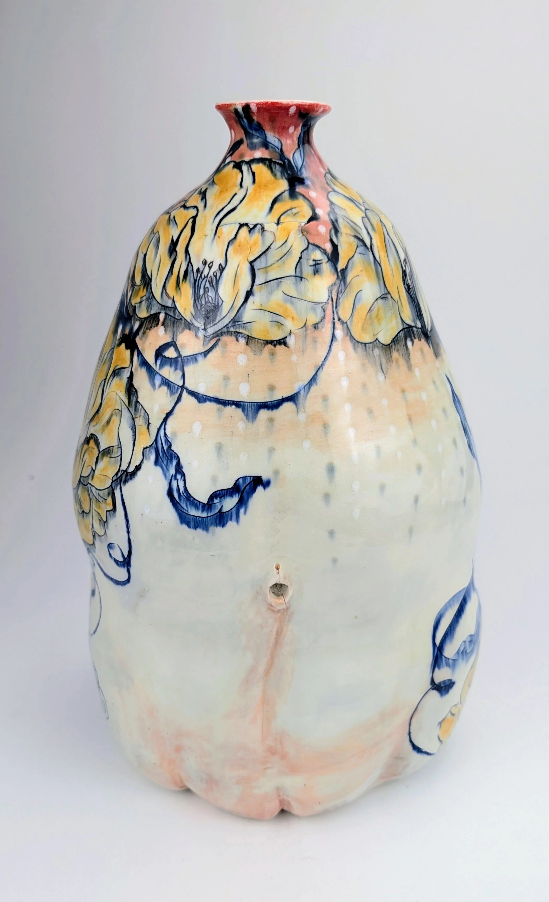 A large ceramic vase with a floral and abstract design in yellow, blue, and orange hues on a white background.