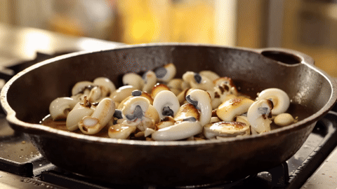 From above hands of unrecognizable woman rubbing aromatic spices into piece of raw meat over parchment paper