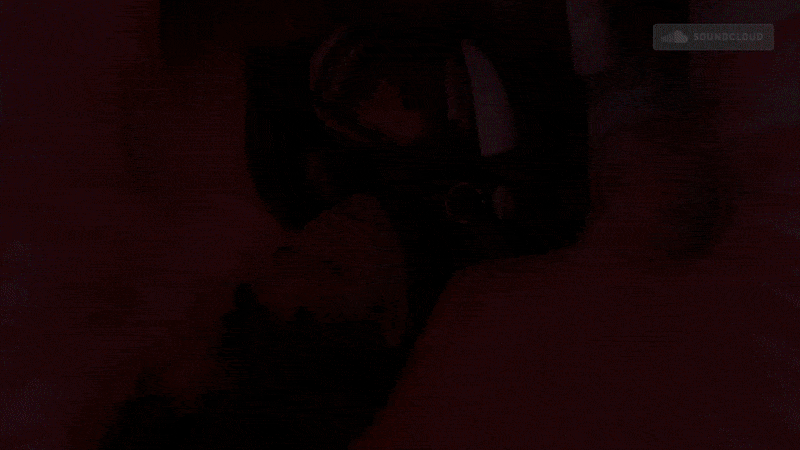 A black gaming headset resting on a red surface with a SoundCloud logo in the top right corner.