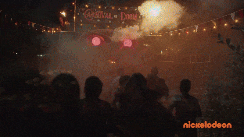 Night scene of a carnival or amusement park with fireworks, smoke, and a crowd watching a fireworks show behind a sign that reads "Carnival of Doom".