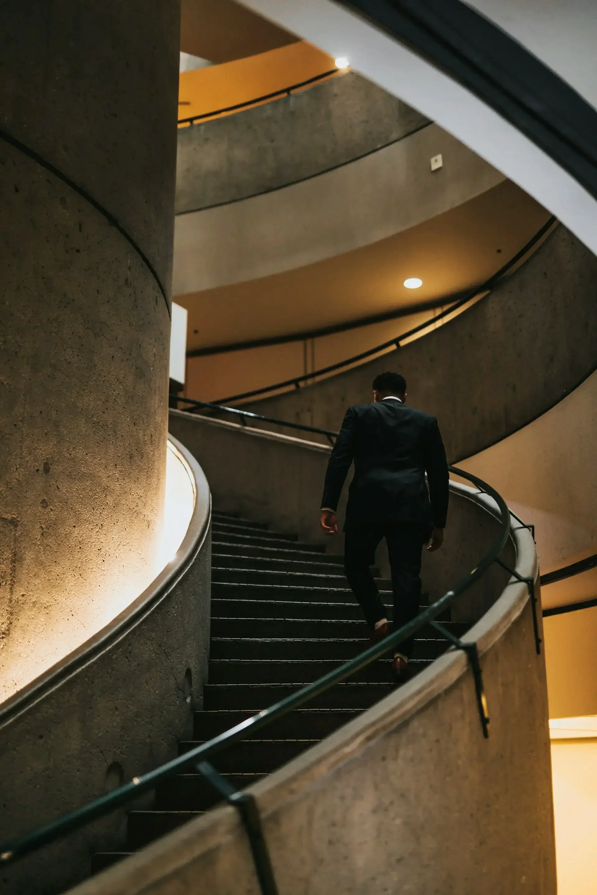 Business professional ascending a staircase, symbolizing a confident next step.