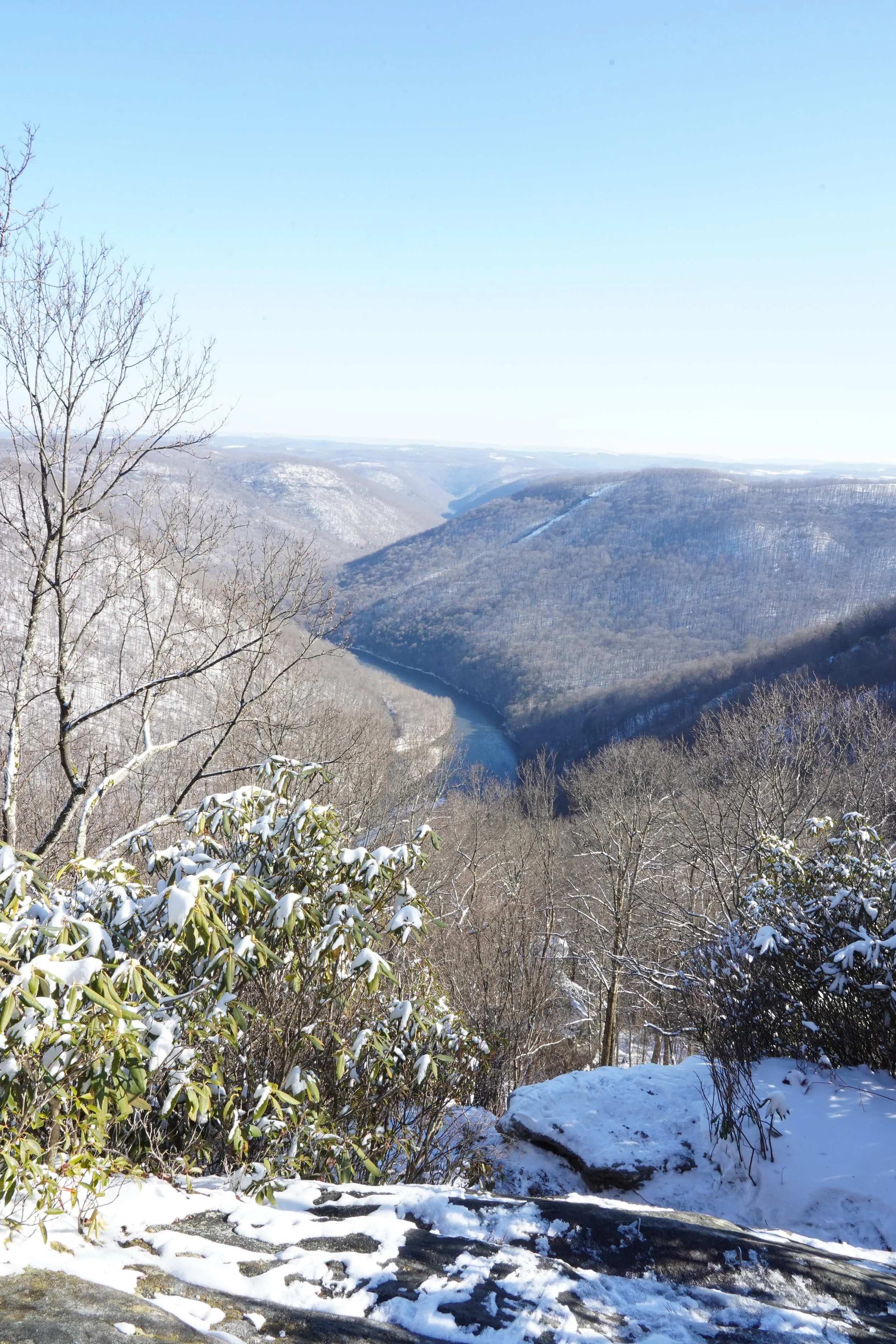 Snow-covered mountains and a river in a winter landscape viewed from a high vantage point.