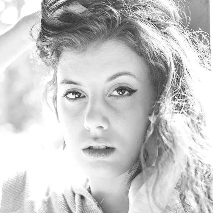 Black and white portrait of a woman with curly hair looking at the camera.