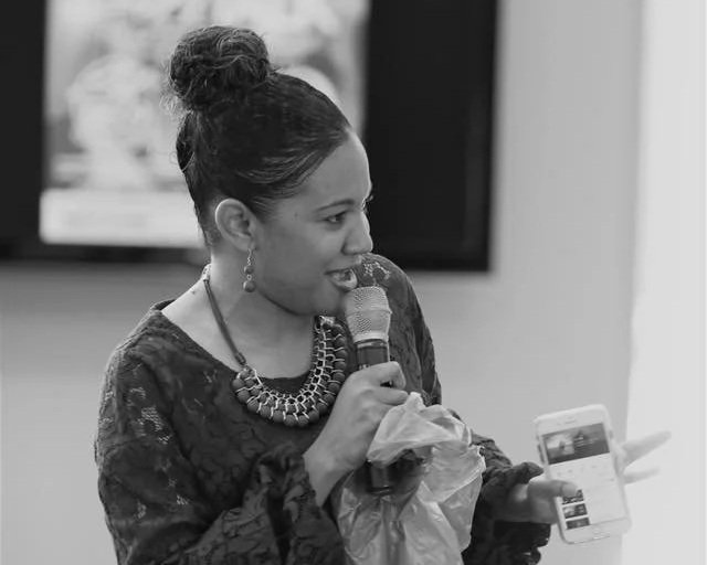 Woman speaking into microphone while looking at her phone