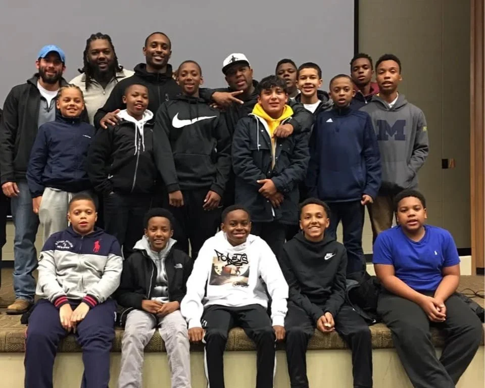 A group of diverse kids and teenagers posing together for a photo indoors, some smiling and making hand gestures.