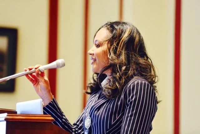 A woman speaking at a podium with a microphone.