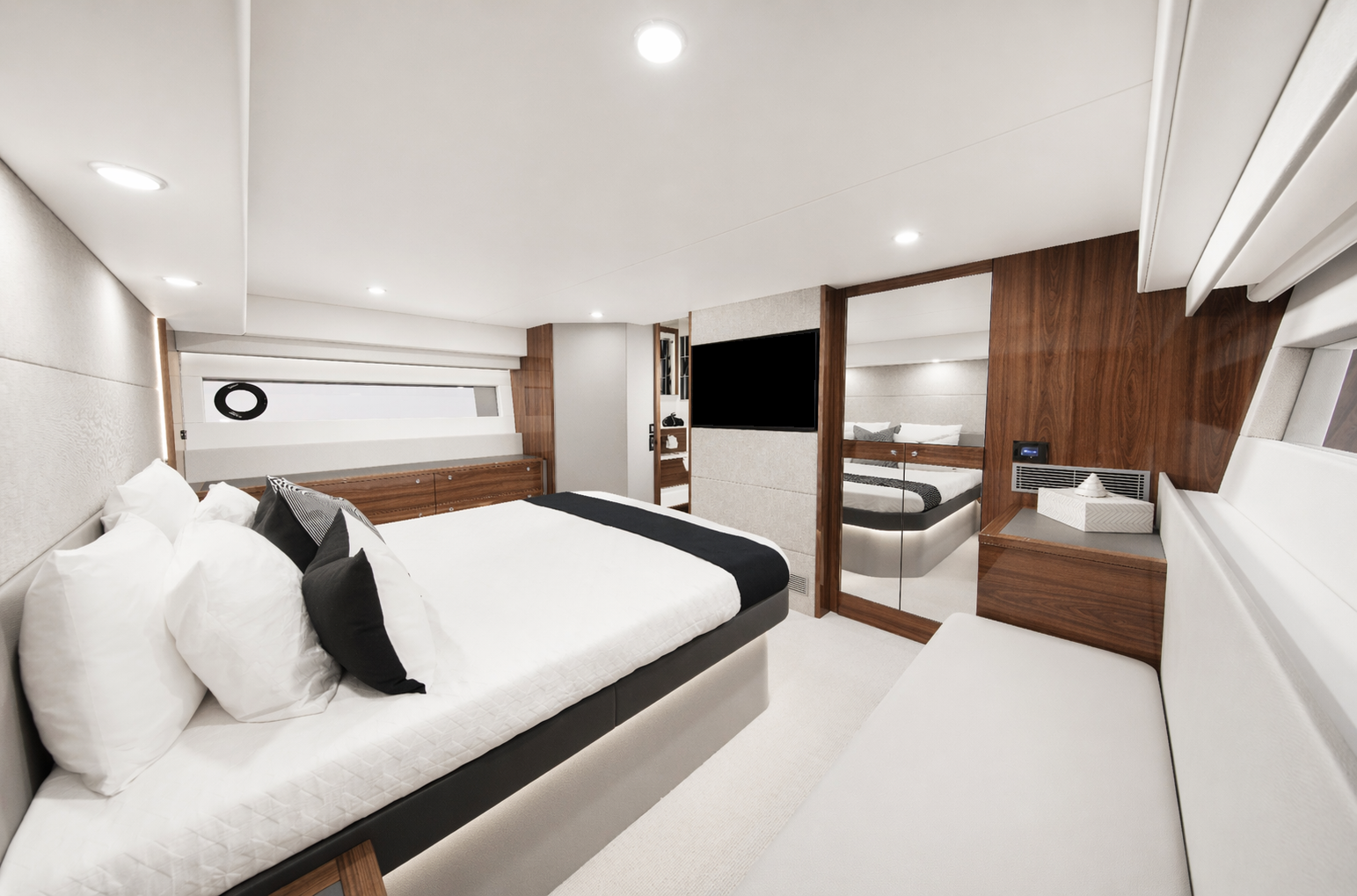 A modern, luxurious bedroom with a large bed with white and black pillows, a white bench, a flat-screen TV, and a mirrored wardrobe.