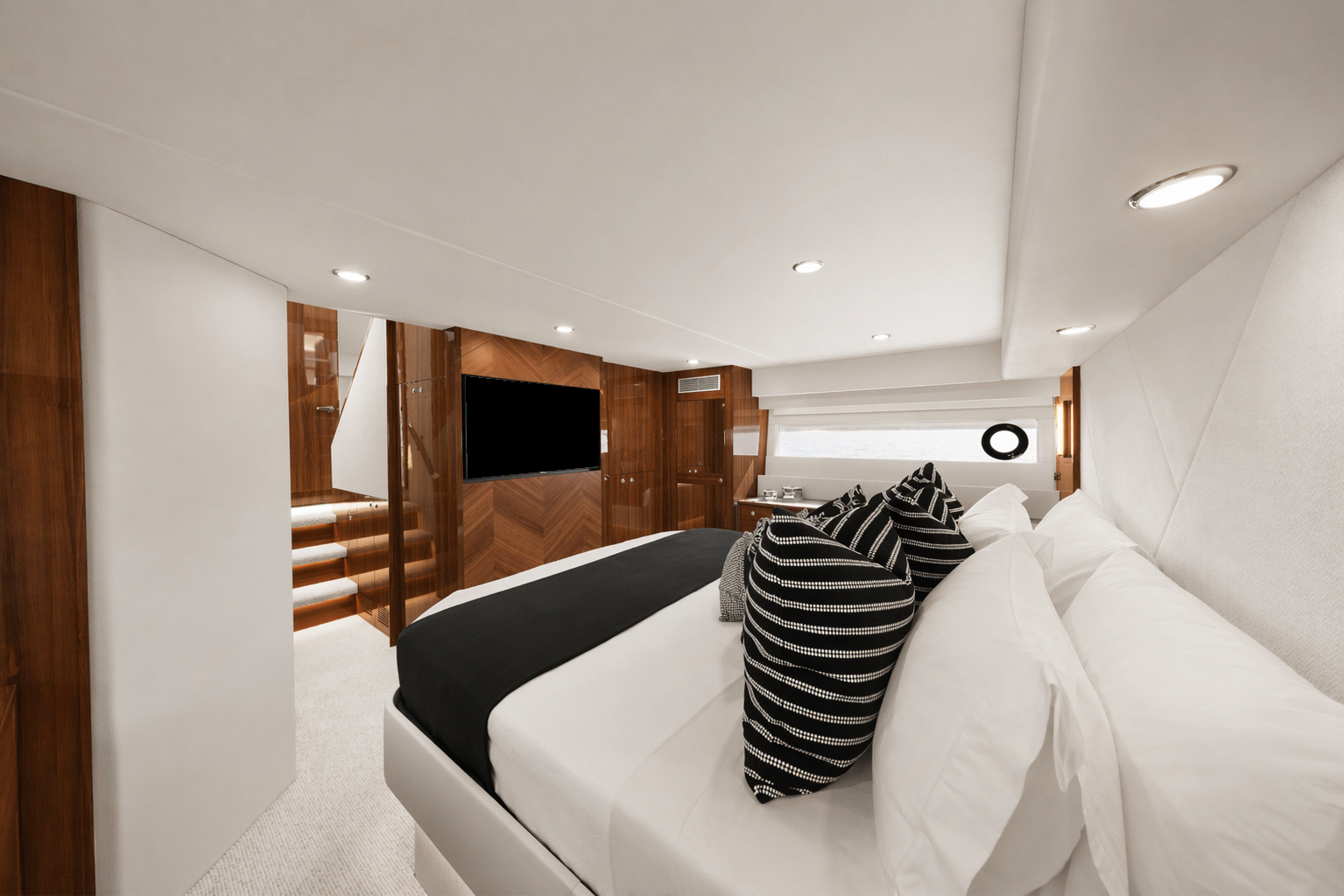 Interior of a luxurious bedroom with a large bed, decorative pillows, and wooden wall paneling, featuring a flat-screen TV and a window with a view.