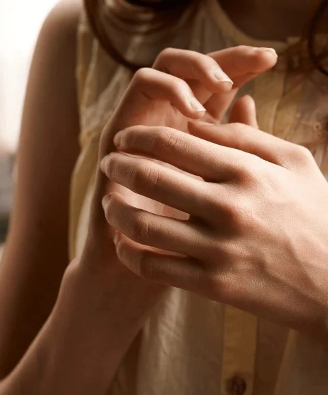 A close-up of hands performing EFT tapping on the side of the hand, in warm, softly lit tones.