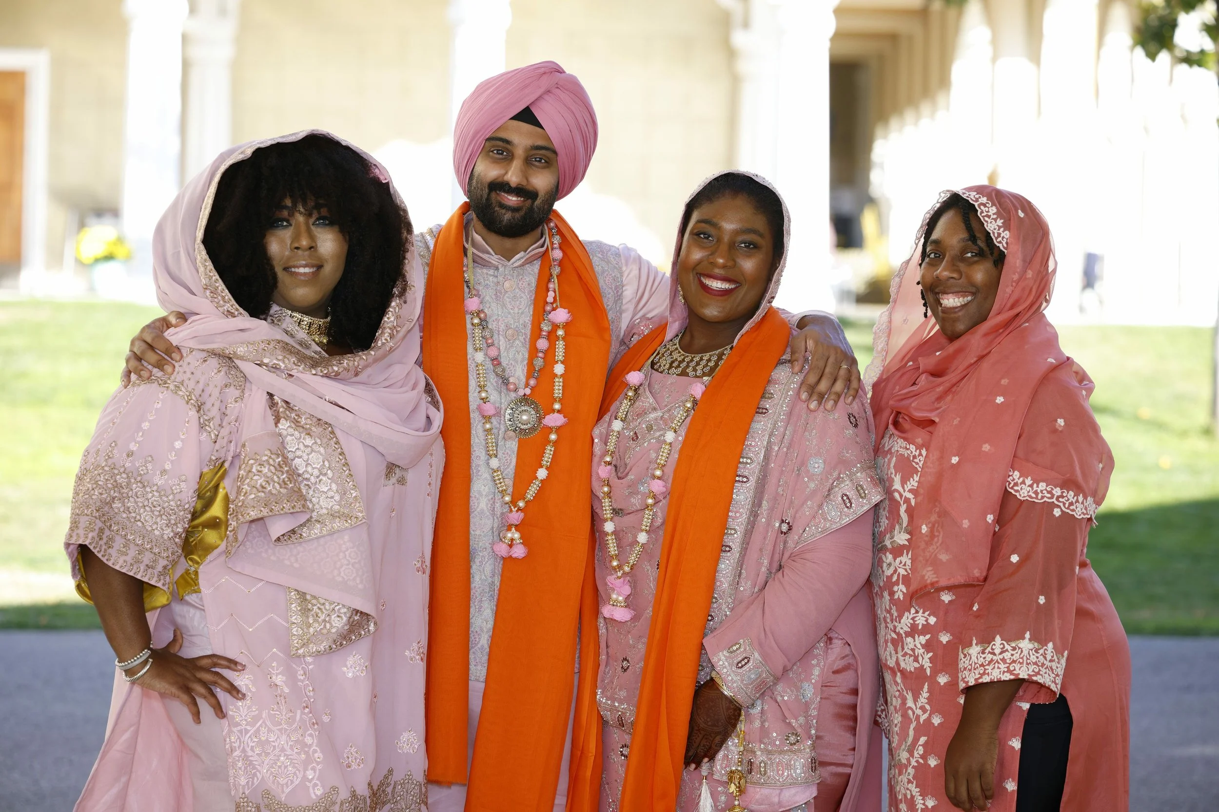 Group of five people dressed in traditional Indian clothing, standing outdoors and smiling for the camera.