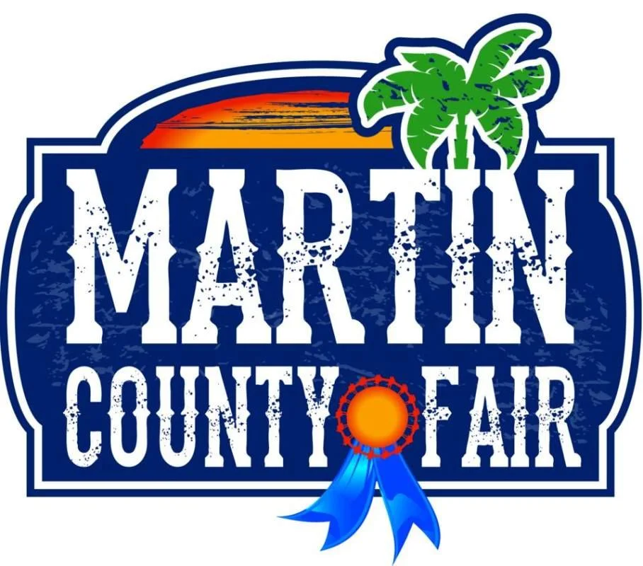 Logo for the Martin County Fair featuring a sunset, palm tree, and a blue ribbon with an orange center.