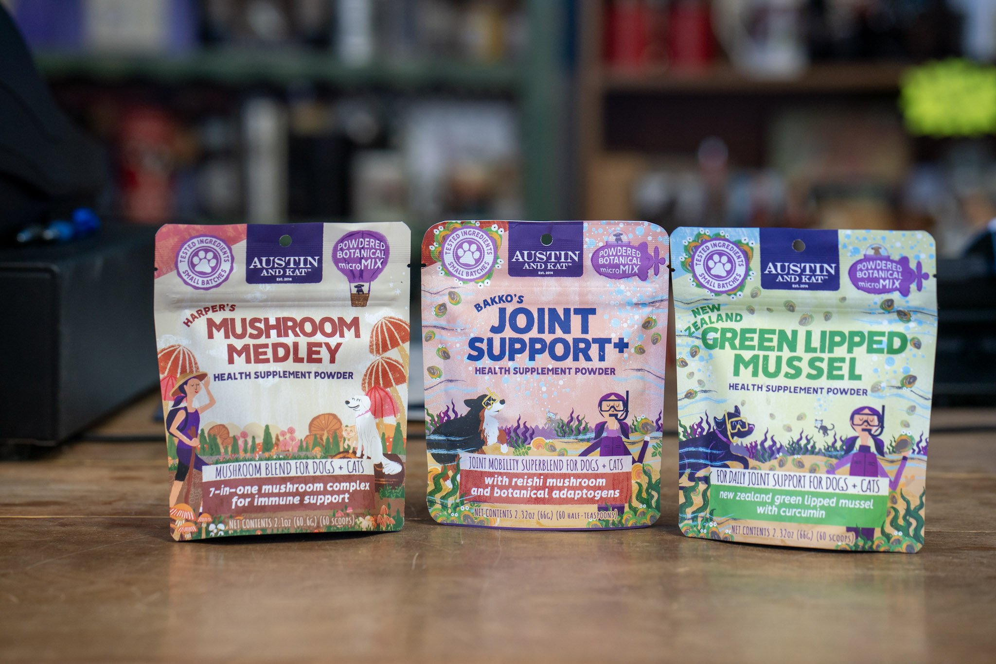 Three packages of Austin and Kat health supplement powders for dogs and cats, featuring Mushroom Medley, Joint Support+, and Green Lipped Mussel.