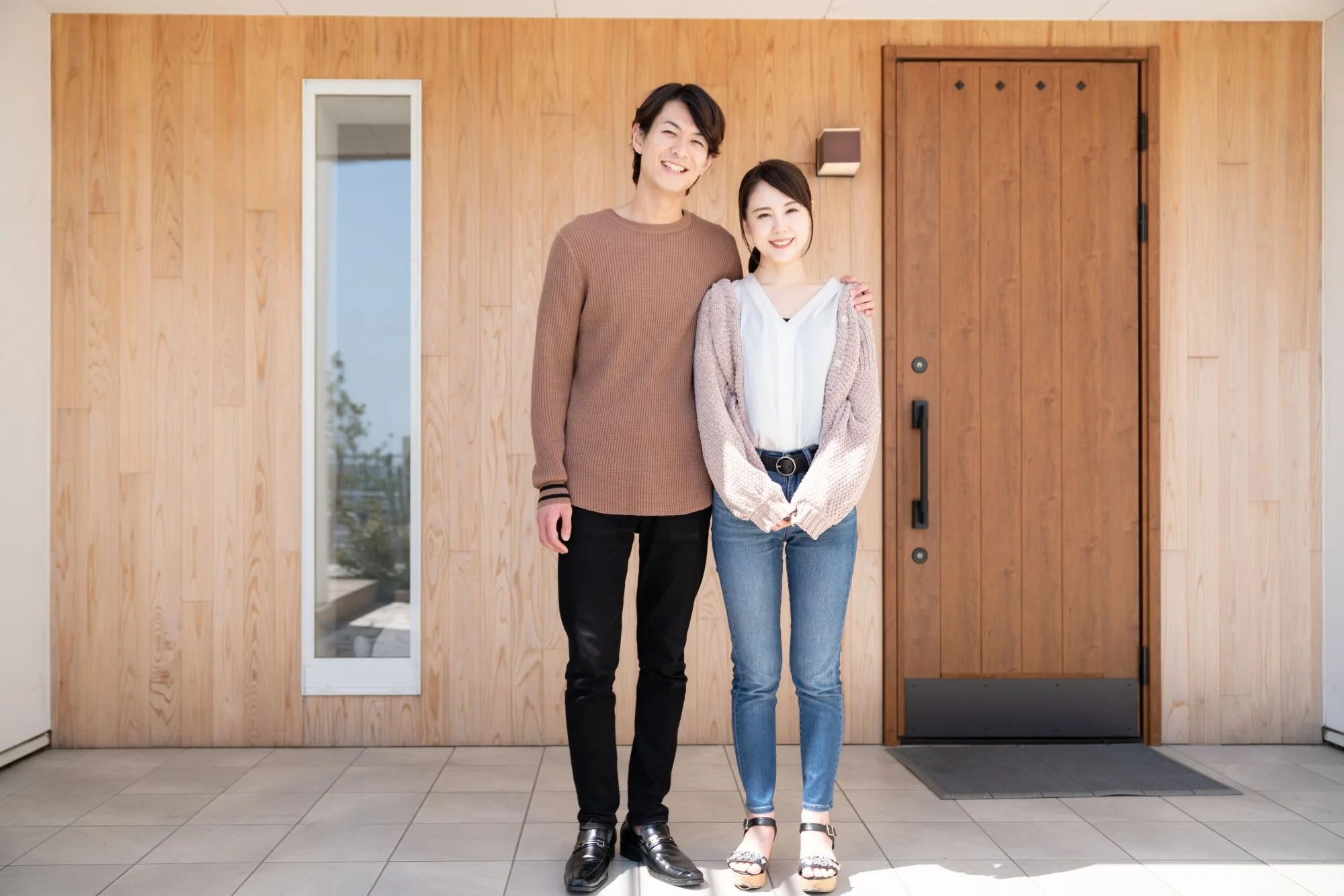 Young couple out front of their new home