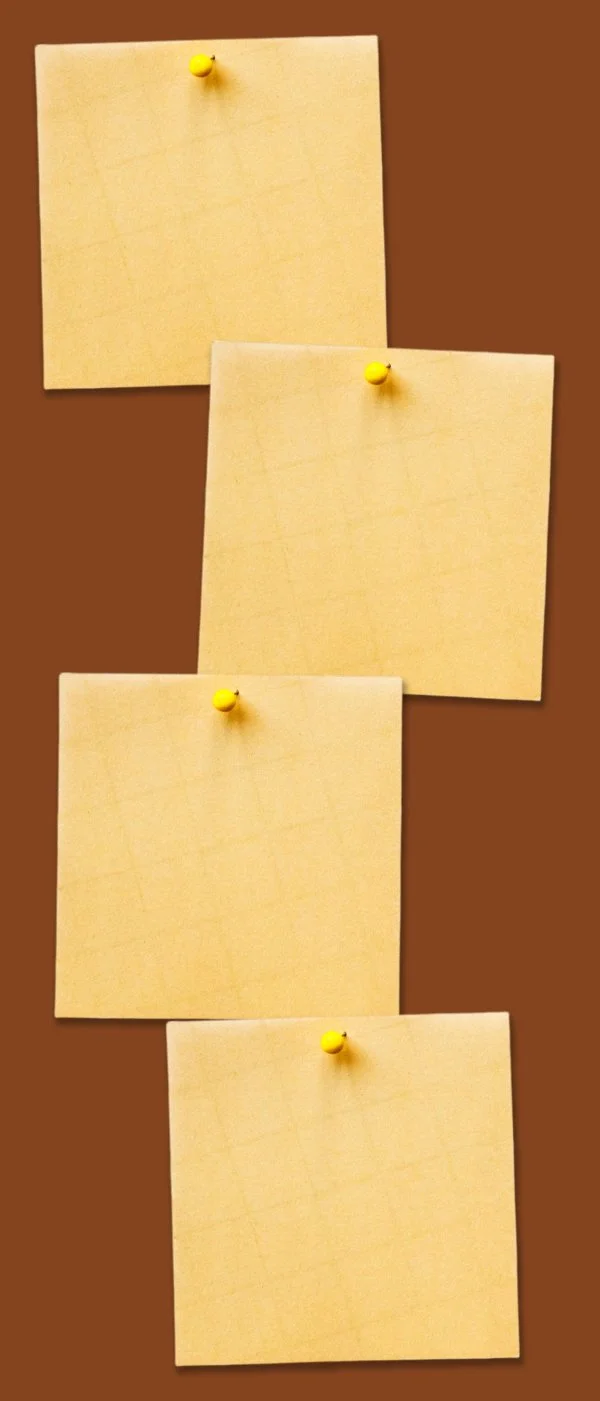 Four yellow sticky notes pinned to a brown corkboard with yellow thumbtacks.