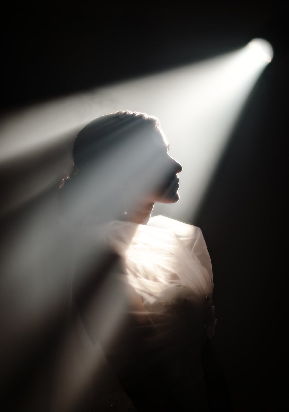 A streak of light falling beautifully on the bride creating a silhouette of her face taken by the photographer Darius N Fernandes