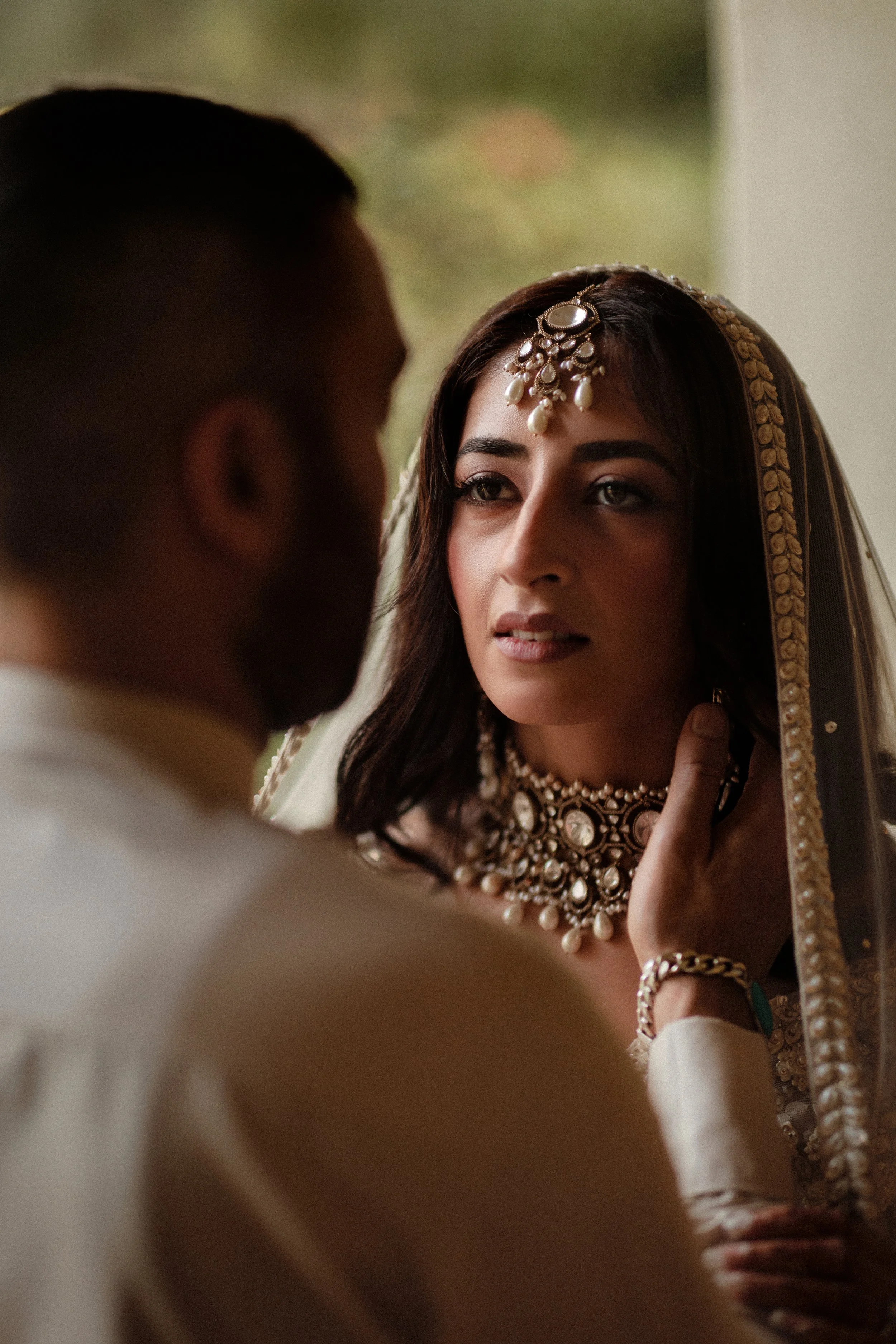 A photograph of the groom lightly caressing the brides face at an indian wedding taken by Darius the photographer