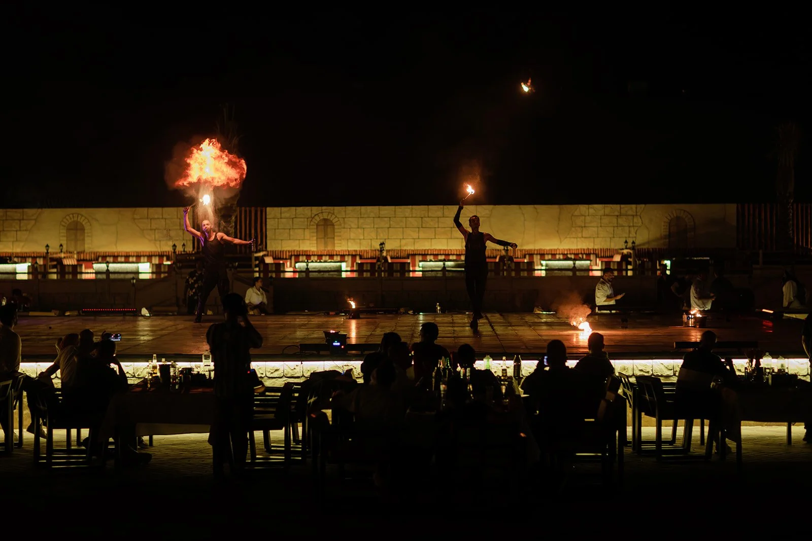 A photograph of an event with fire dancers performing with fire and the crowds gathering around and watching them