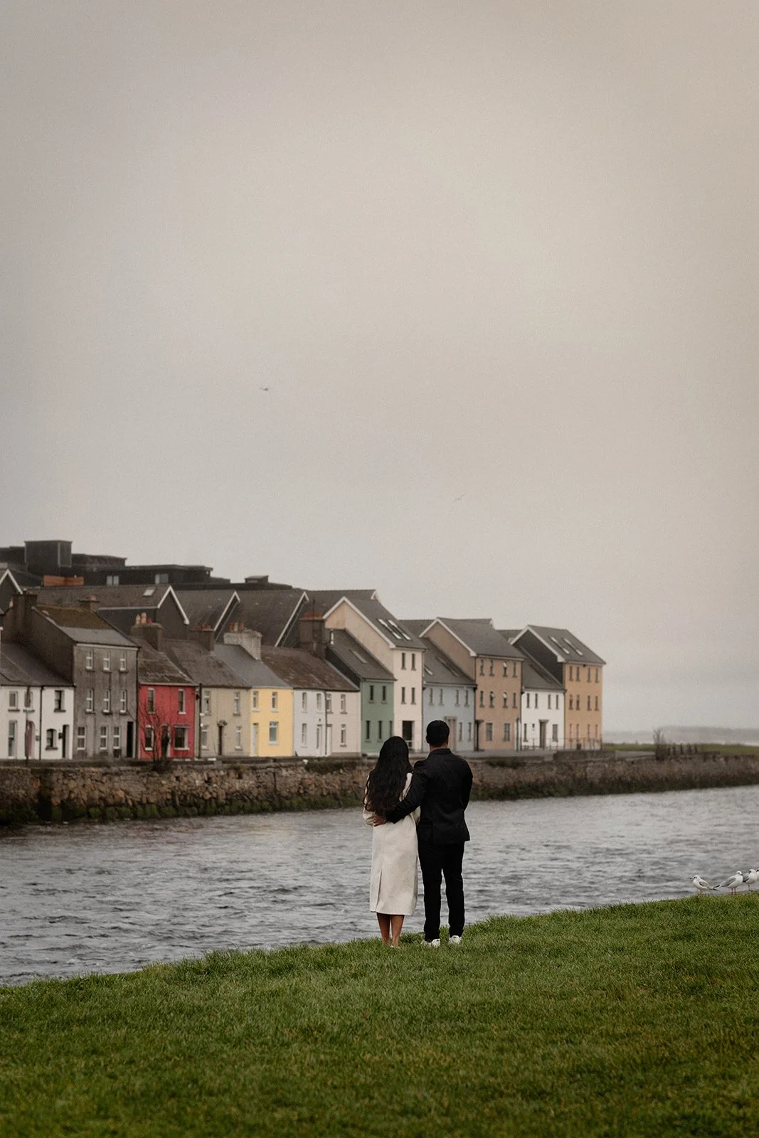 A photograph of the couple with his arm around her and colorful houses in the background