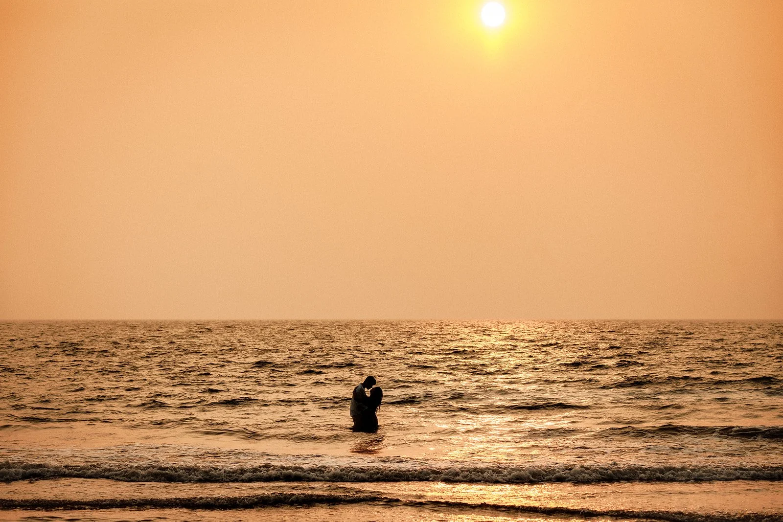 A photograph of the couple enjoying by the sunset in the water at a beach in Goa Shot by Darius from the Netherlands